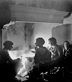 an old image of Italian farmers cozying up next to an old limestone fireplace mantel